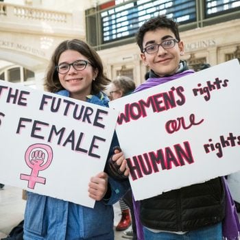 two young people holding signs. One says "the future is female." the other sign says "women's rights are human rights"