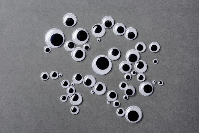 Many different sizes of googly eyes on grey background.
