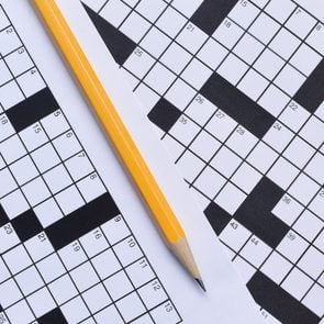 empty paper crossword puzzle with pencil in between