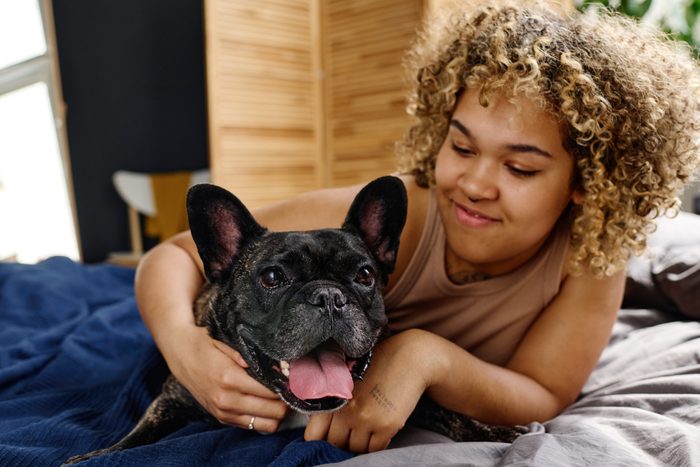 Young woman relaxing in bed with dog