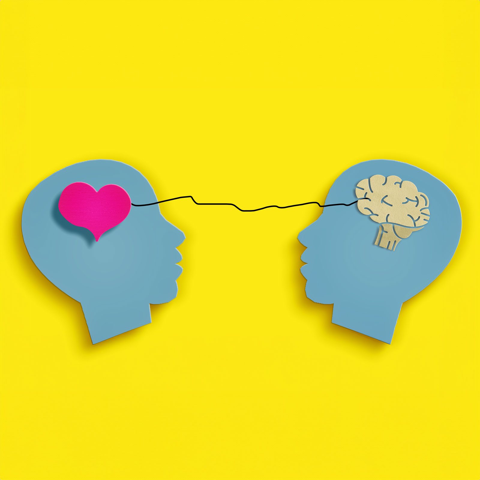 two paper heads one with a heart and one with a brain on a yellow background
