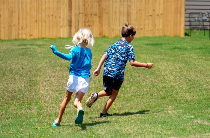 Girl Chasing Boy in Backyard - Color