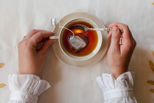Hands stirring cup of tea