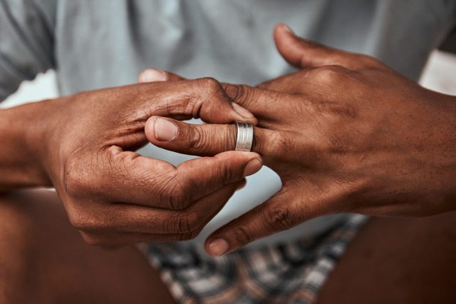 Divorce, breakup and wedding ring with hands of person in bedroom for fight, conflict and sad. Jewelry, doubt and affair with closeup of man and engagement band at home for angry, problem and loss