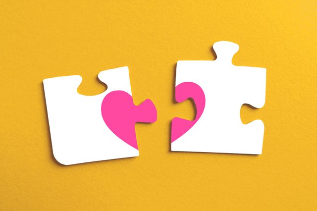 two disconnected puzzle pieces with pieces of a heart on a yellow background