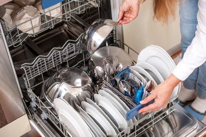 Adult Woman Unloading Dishwasher In The Kitchen