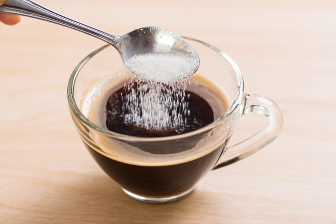 Pouring sugar into coffee cup