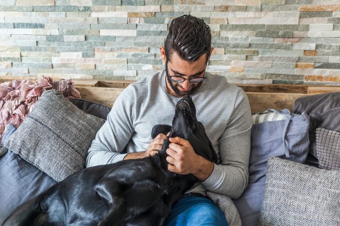 Man cuddling with his dog on the couch at home