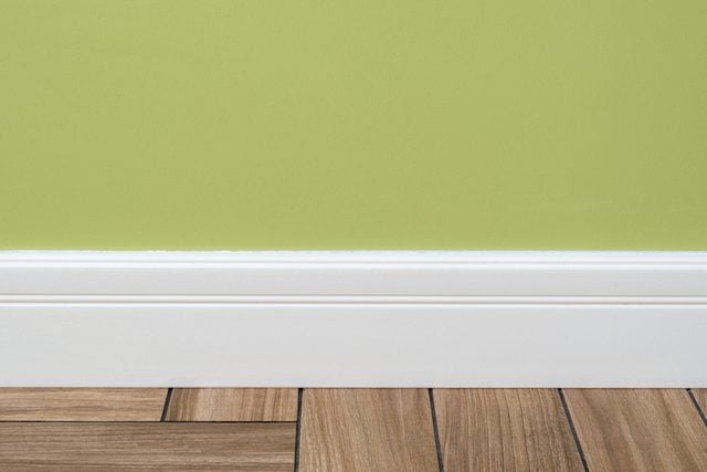 green wall with a white baseboard in a house
