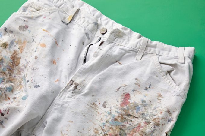 White jeans with a lot of dried paint stains on green background