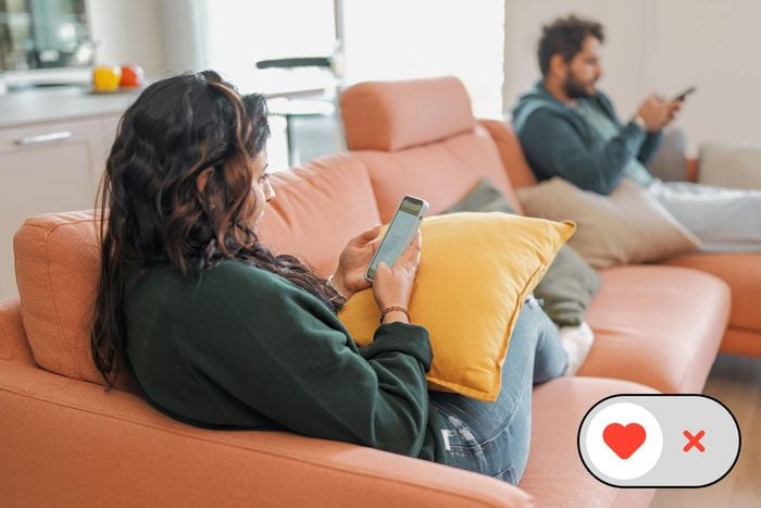 a couple sitting on opposite ends of the couch, both on their phones