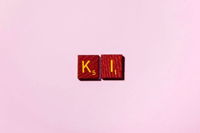 "KI" in scrabble letters on a pink background