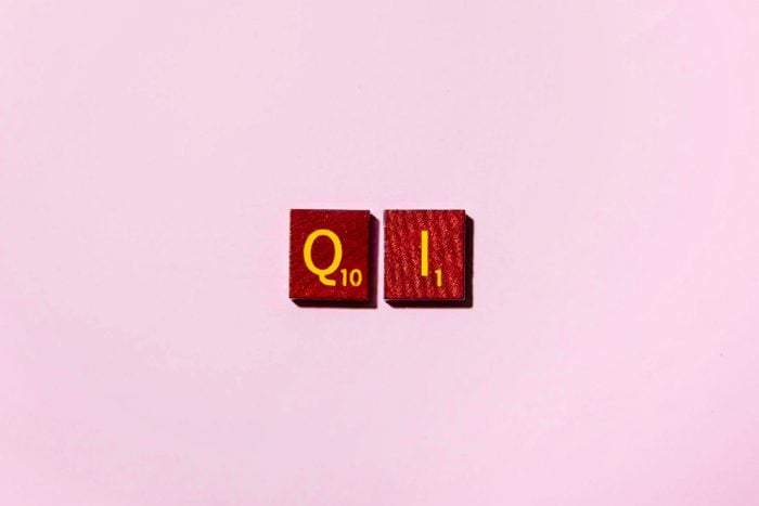 "QI" in scrabble letters on a pink background