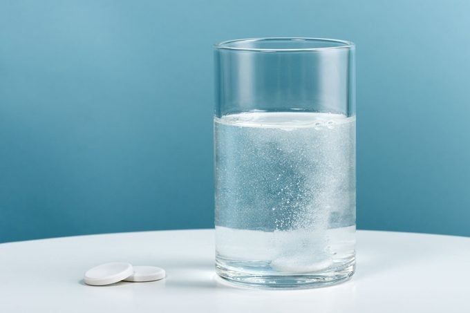 A Glass Of Water With Denture Tablet On Blue Background