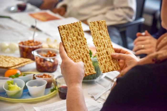 hands breaks a piece of unleavened bread at an Interfaith Passover seder