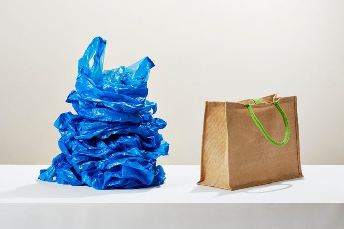 A stack of blue plastic bags next to a reusable shopping bag tote