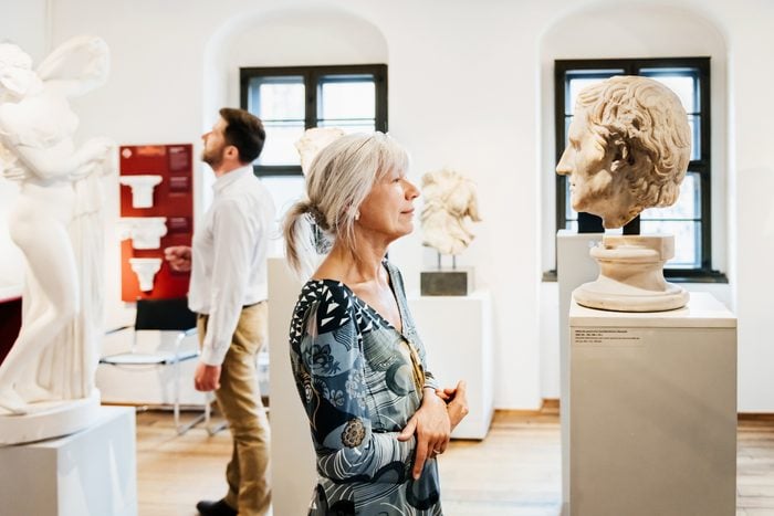 Mature Woman Looking At Sculpture In Historical Museum