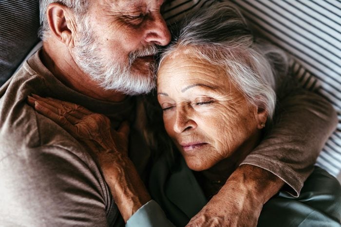 Older couple embracing while lying down