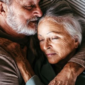 Older couple embracing while lying down