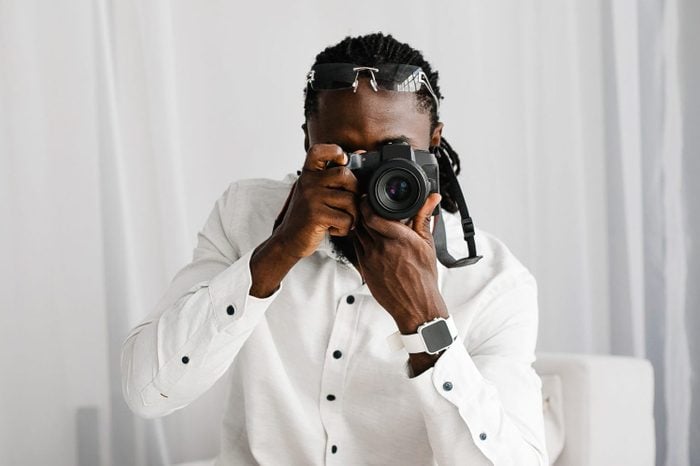Handsome young African-American man photographer shooting with professional camera.