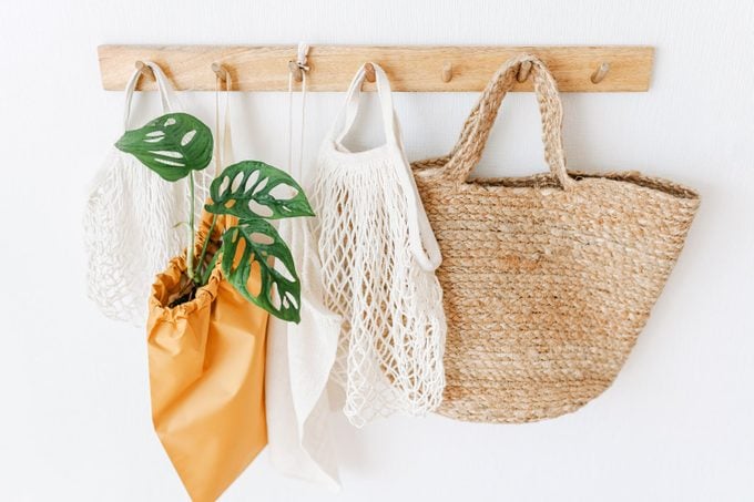 Variety of Eco-Friendly Reusable Bags Hanging On Coat Hook against a white wall