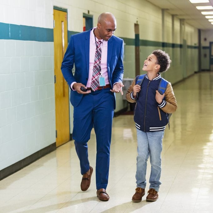 Elementary student walking with teacher in school hallway