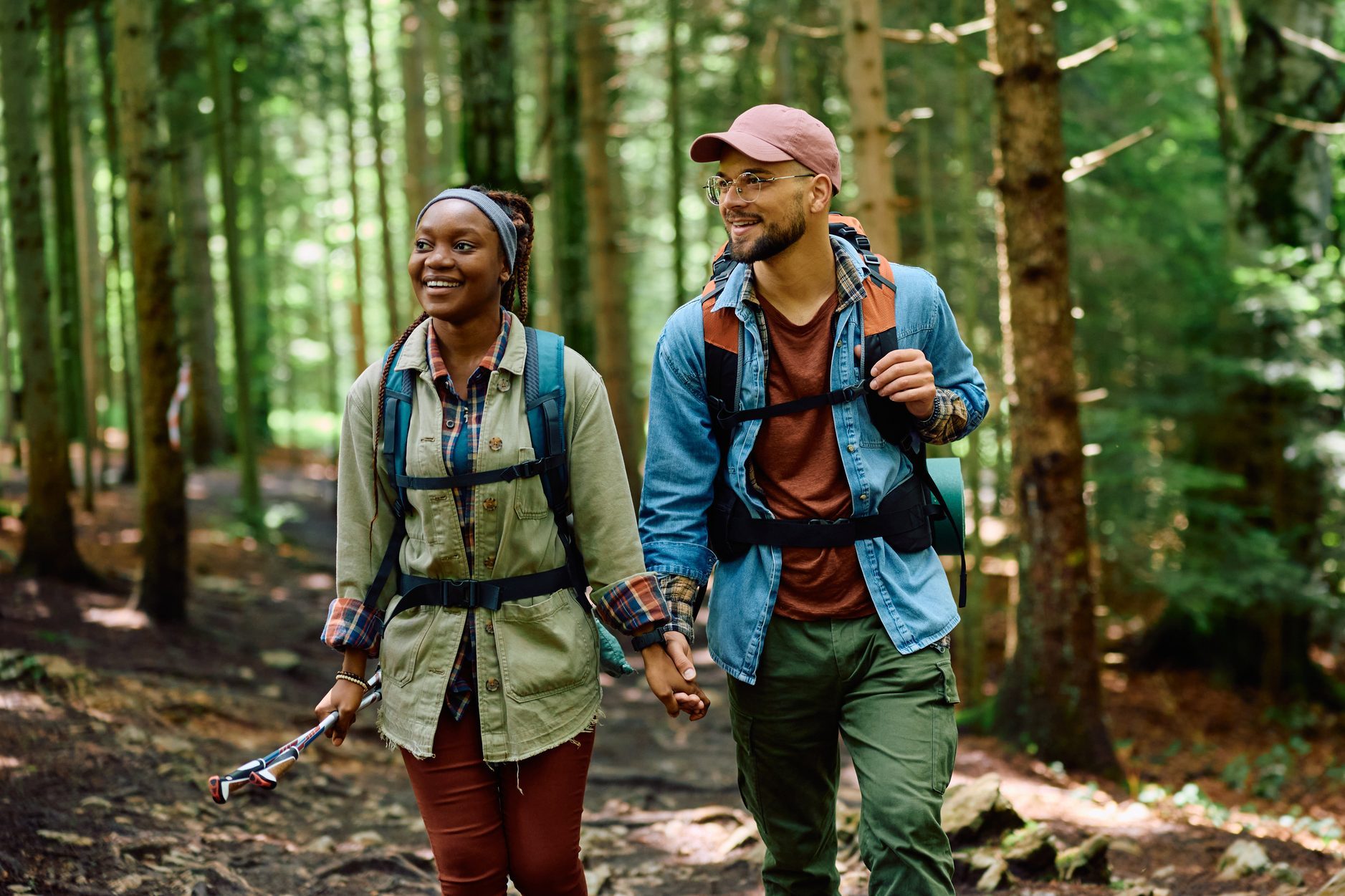 Happy couple of hikers holding hands while walking through the woods.