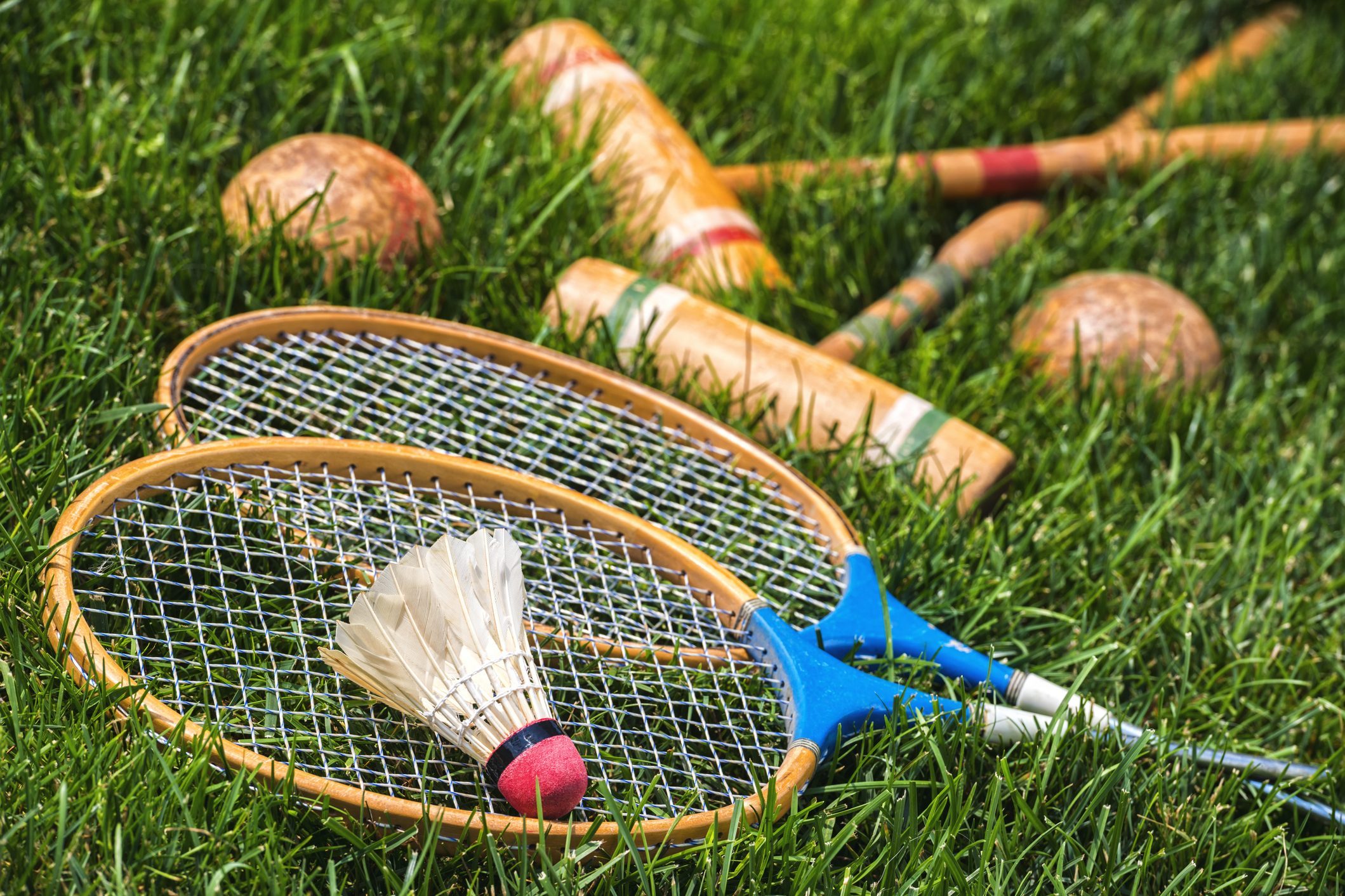 Vintage badminton rackets and croquet mallets lying in grass