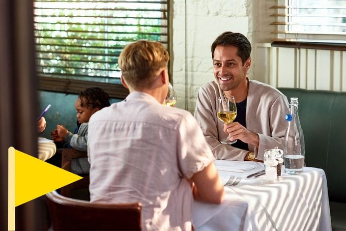 two men drinking wine and having a nice date with a yellow flag icon in he bottom left corner