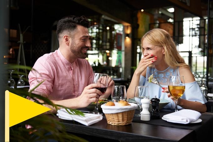 man and woman laughing on a date with a yellow flag icon in he bottom left corner